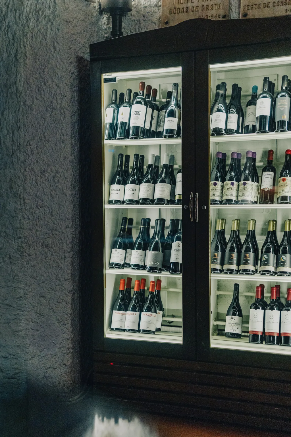A garrafeira iluminada, encastrada na parede de pedra