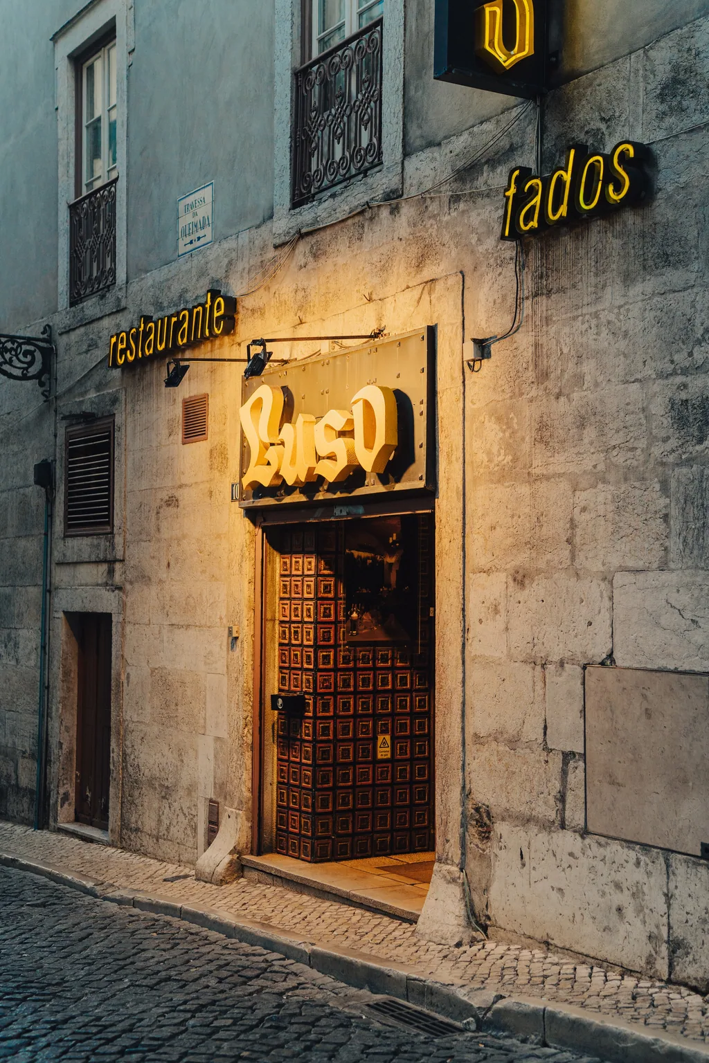 A porta do Café Luso aberta à noite, com o letreiro aceso