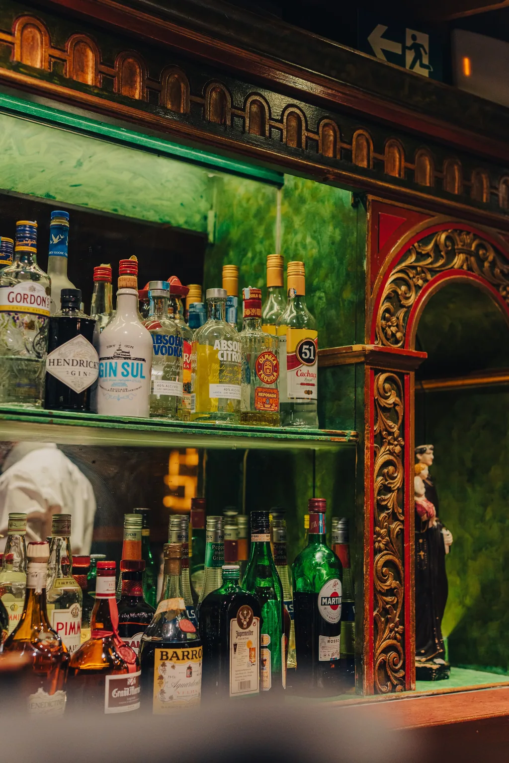 Die Flaschen der Bar unter der grün-goldenen Tafel