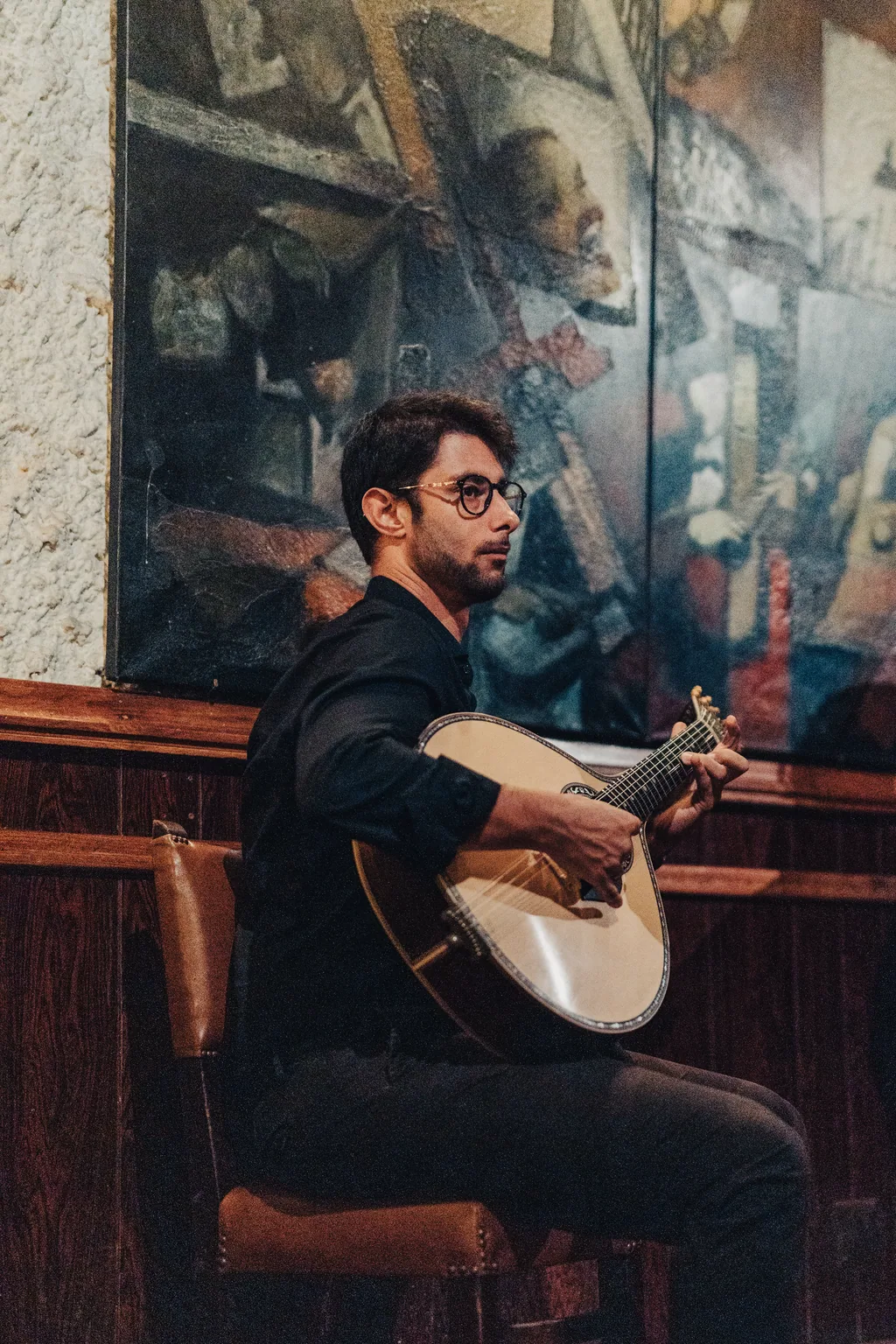 Guitarrista junto ao mural da sala
