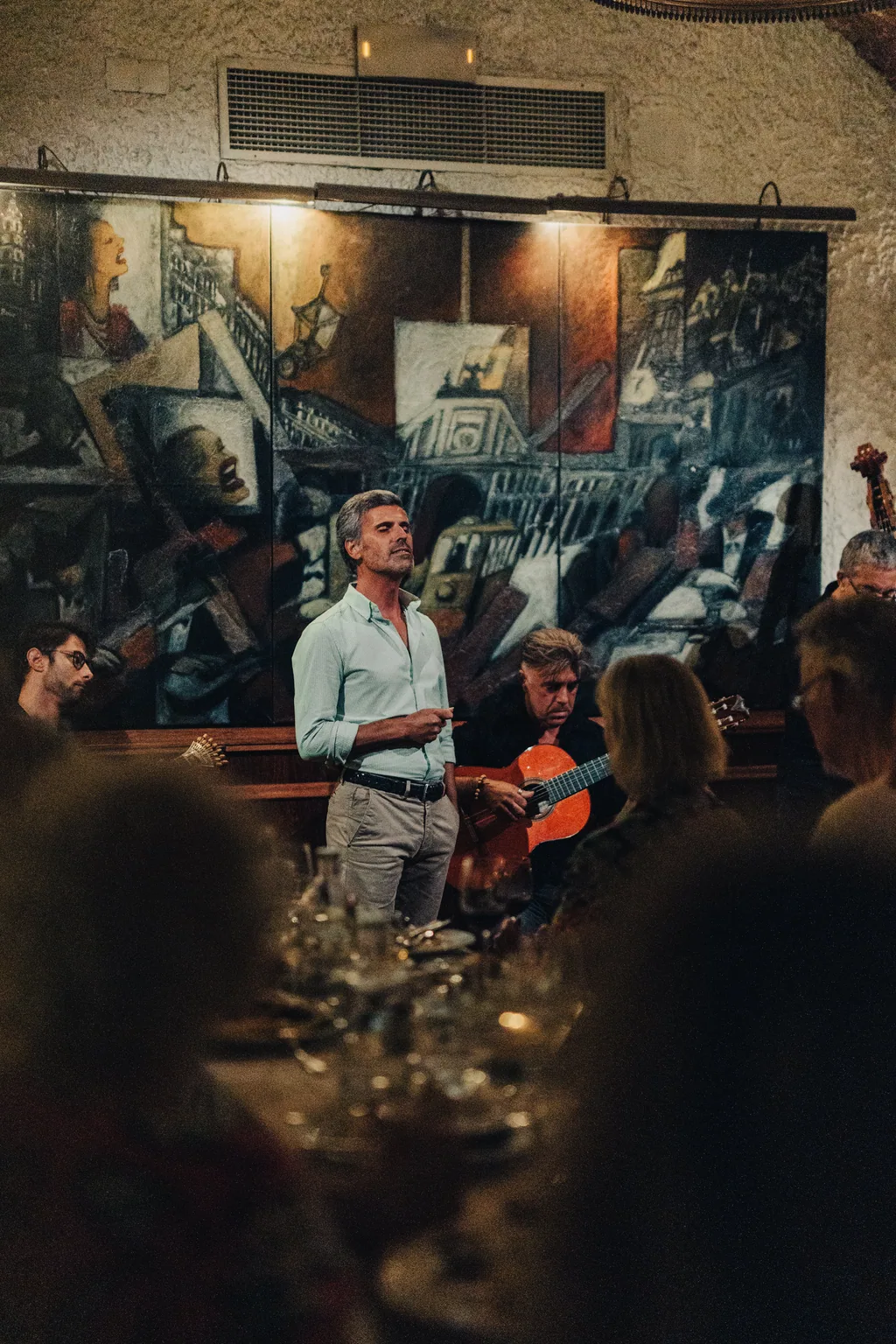 Il fadista canta davanti al murale, con il contrabbasso accanto