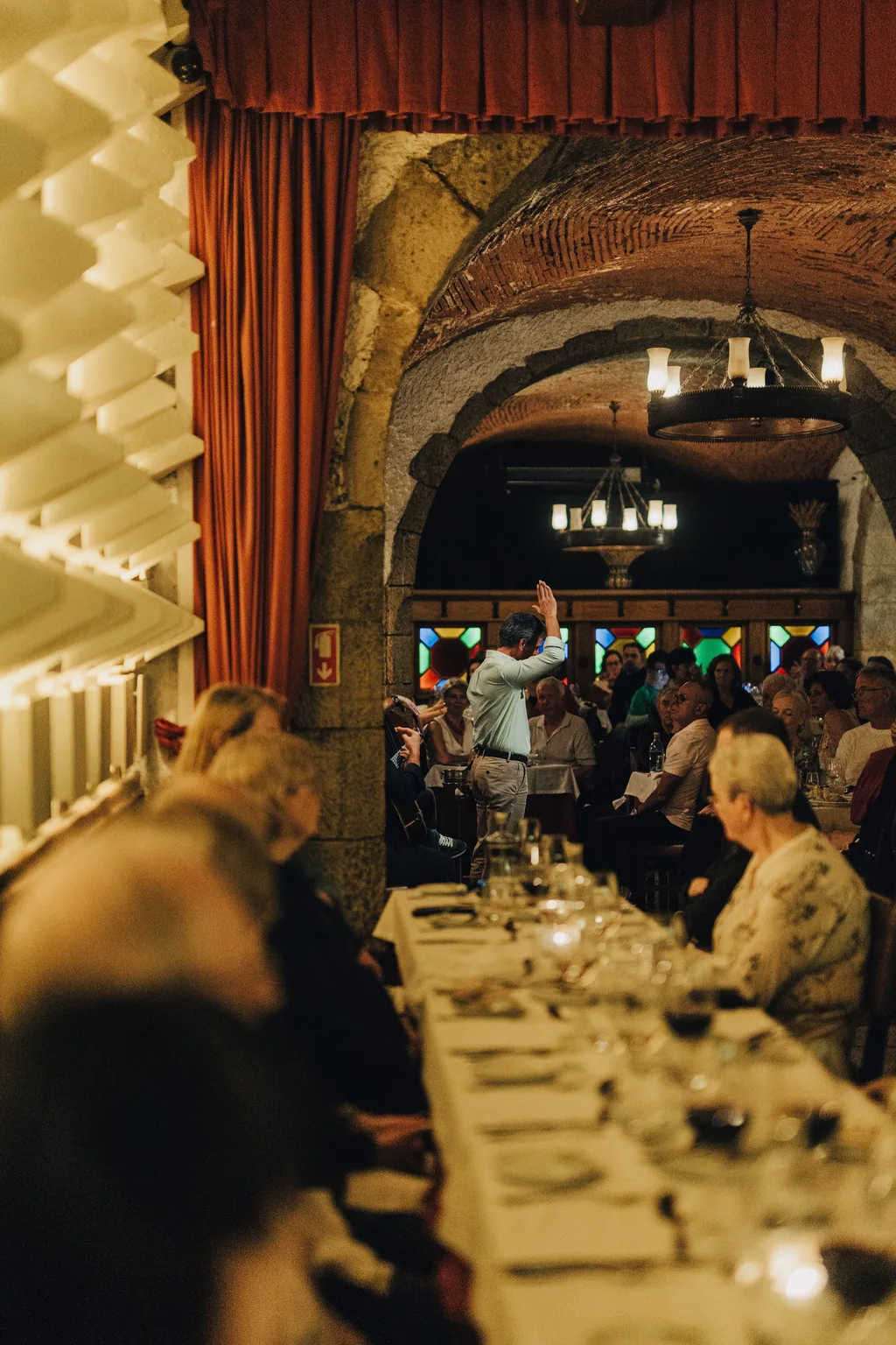 Die lange Tafel besetzt, unter dem Steingewölbe