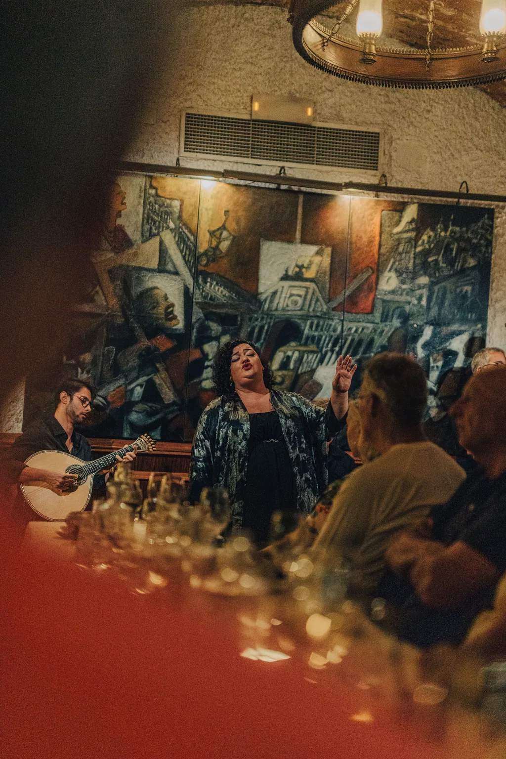 Fadista e musicisti accanto al murale del Café Luso, in piena esibizione
