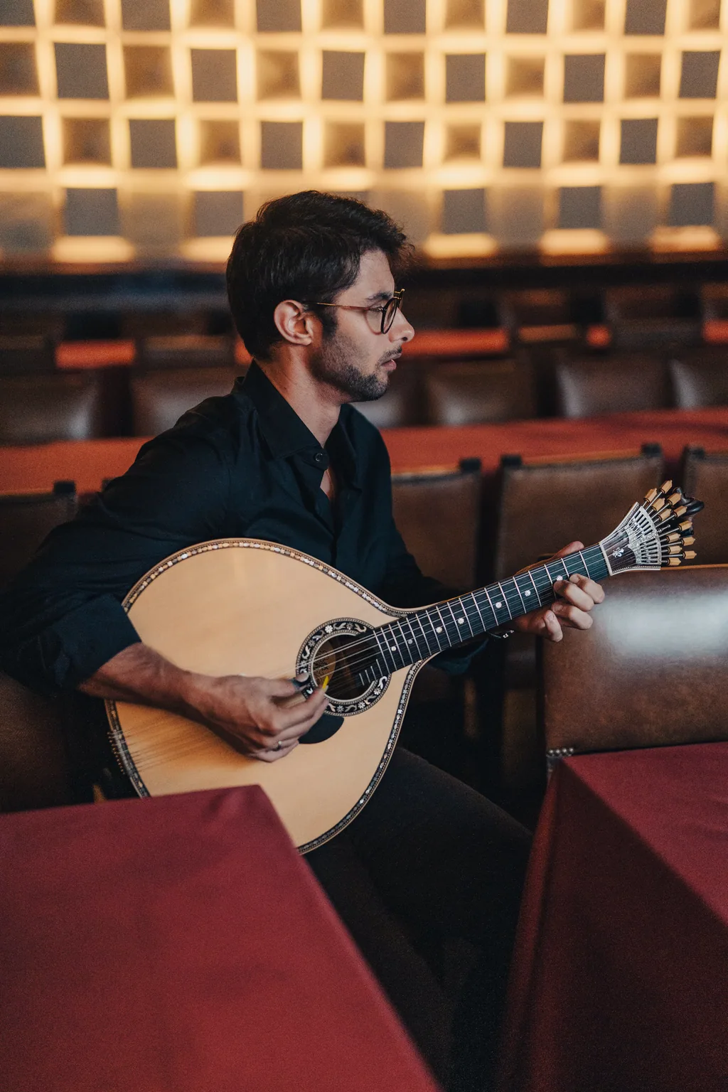 Músico com guitarra portuguesa nas cadeiras de couro