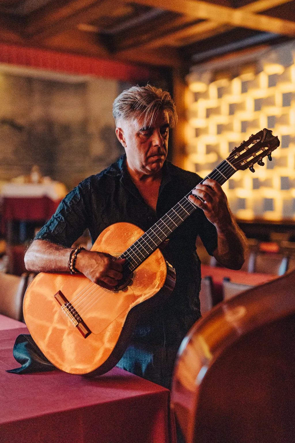 Guitarrista diante da parede de relevo da sala